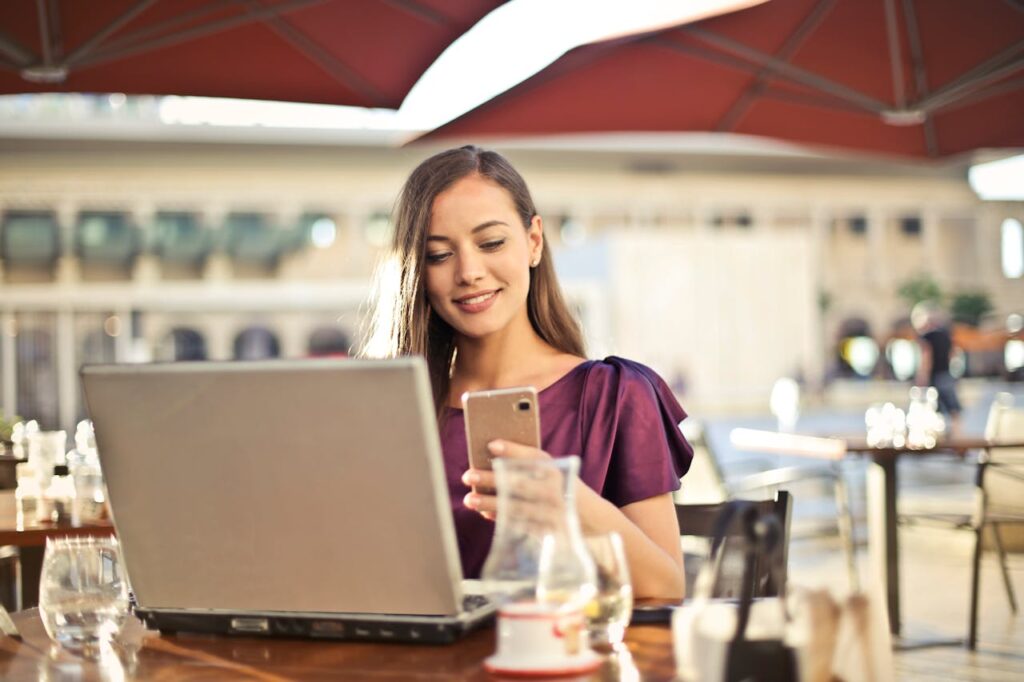 Frau arbeitet mit Laptop und Smartphone Wie Bilder verschicken ohne Qualitätsverlust